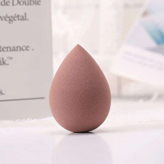 Pink makeup sponge on a white surface with blurred background