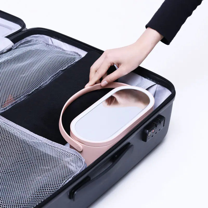 Person placing a pink electronic device into a black travel case with compartments.