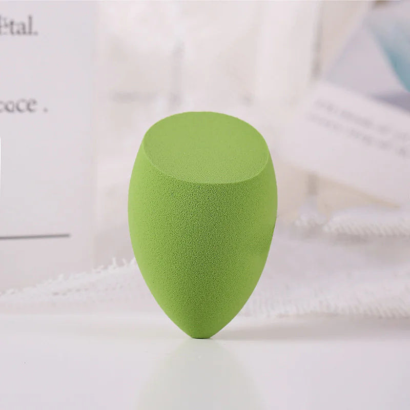 Green makeup sponge on a white surface with a blurred background