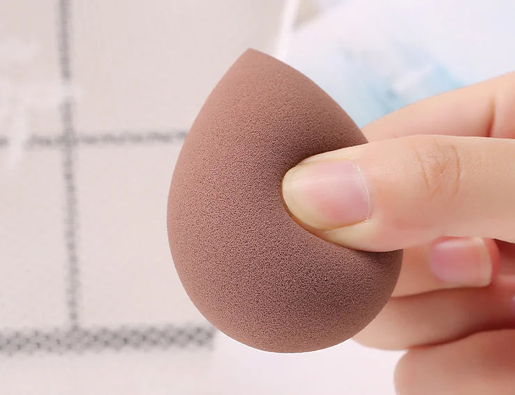 Makeup sponge held by a hand with a blurred background