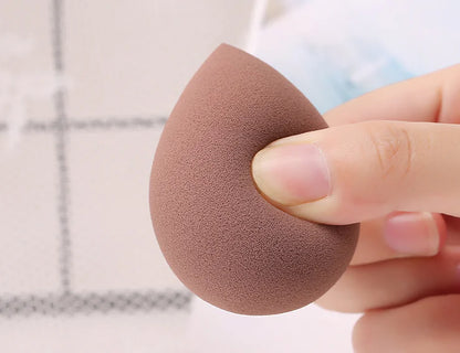 Makeup sponge held by a hand with a blurred background