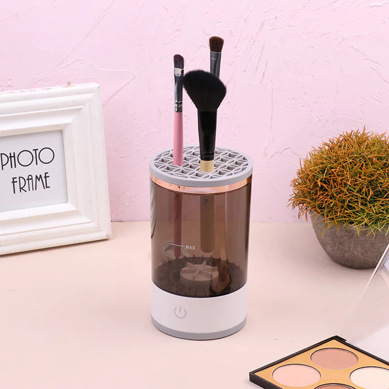 Makeup brush holder with brushes on a desk next to a photo frame and plant