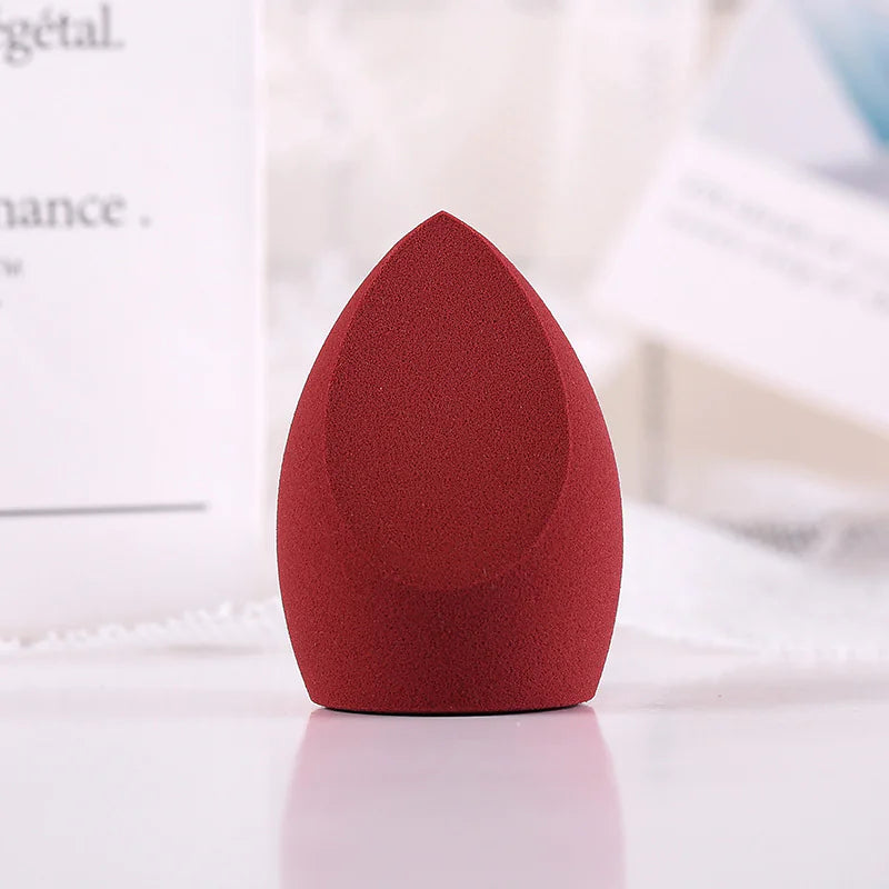Red makeup sponge on a white surface with a blurred background