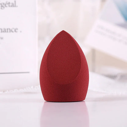 Red makeup sponge on a white surface with a blurred background