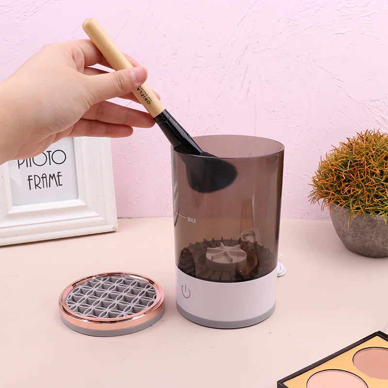 Hand holding a brush over a cylindrical device with a pink background