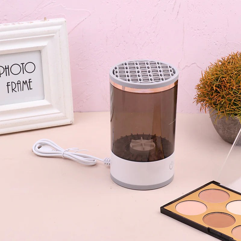 Small cylindrical device with a white base and transparent top on a pink surface with a photo frame and plant in the background.