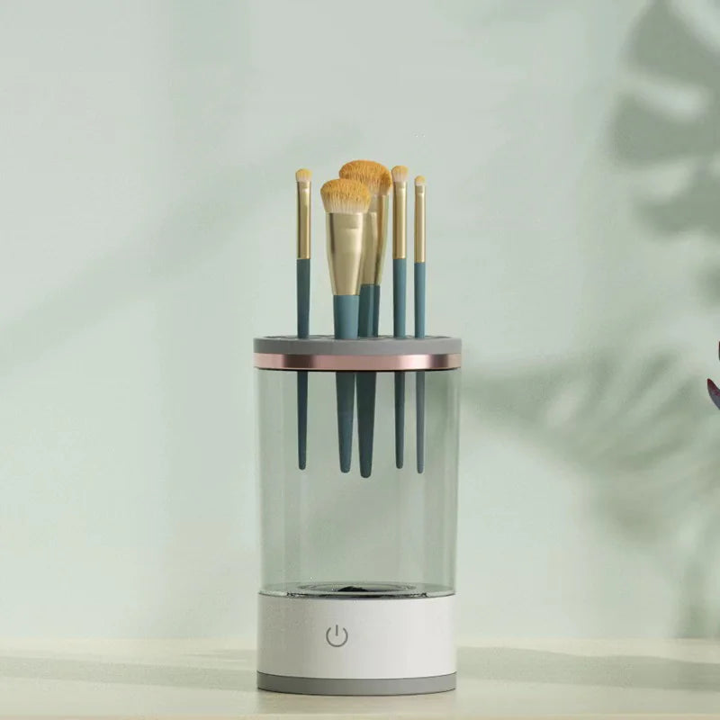 Set of makeup brushes in a clear cylindrical holder on a light background